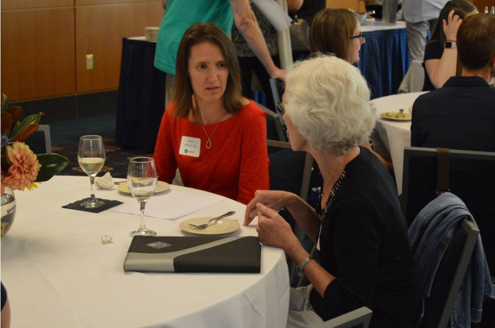Two alumnae talking at a table